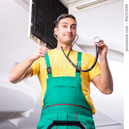 Young repairman repairing ceiling air conditioning unit 99225849