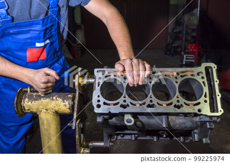 Auto mechanic repairing a cylinder block in a garage. Auto repair concept Auto mechanic repairing a cylinder block in a garage. Auto repair concept 99225974
