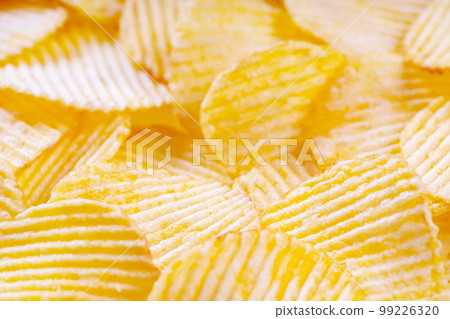 Yellow crispy ridged potato chips close up. Food background 99226320
