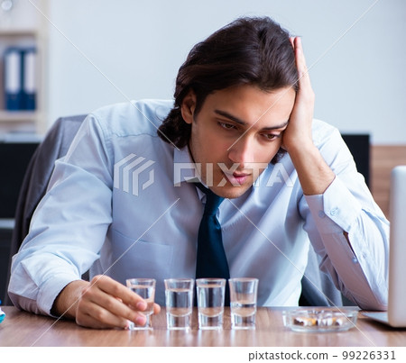 Male employee drinking vodka and smoking cigarettes at workplace 99226331