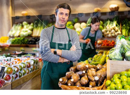Male salesman near fruit and vegetables stalls offering to buy yuca 99228698