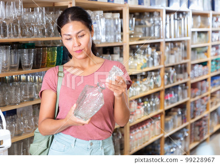 Asian woman choosing glassware in store Asian woman choosing glassware in store 99228967