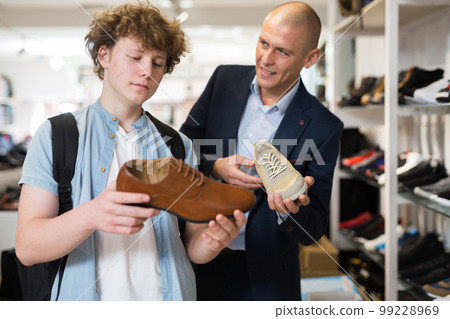 Man and teenage boy choosing dress shoes in shoe boutique Man and teenage boy choosing dress shoes in shoe boutique 99228969