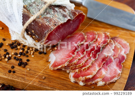 Sliced jerky pork tenderloin with spices on wooden background 99229189