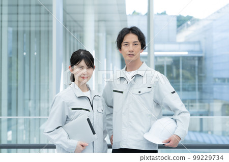Portrait of two young male and female workers 99229734