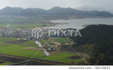Passenger train towed by DD51 running with Lake Nishinoko and Azuchi Castle ruins in the background (Tokaido Main Line, Azuchi-Notogawa, February 2023) 99230692