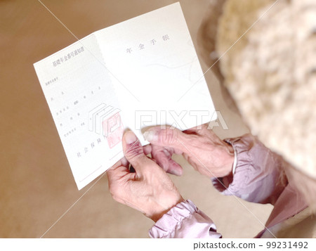 Elderly woman's hand holding an open pension book 99231492