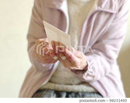 Elderly woman's hand holding an envelope Elderly woman's hand holding an envelope 99231493