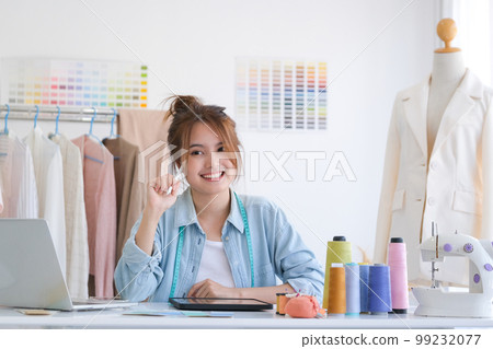 Young asian female fashion designer is sitting at her desk at design studio. 99232077