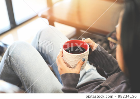 Morning relaxation girl sitting and enjoying coffee leisure time happy woman relaxing in home on winter, Woman relaxing at home and sitting on sofa and looking drinking coffee Morning relaxation girl sitting and enjoying coffee leisure time happy woman relaxing in home on winter, Woman relaxing at home and sitting on sofa and looking drinking coffee 99234156