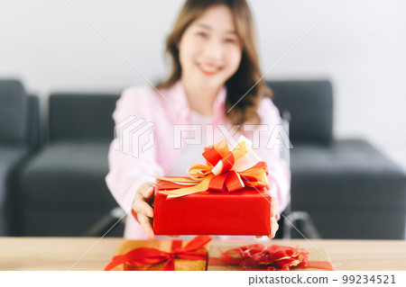 Closedup red gift box present from happy smile asian woman 99234521