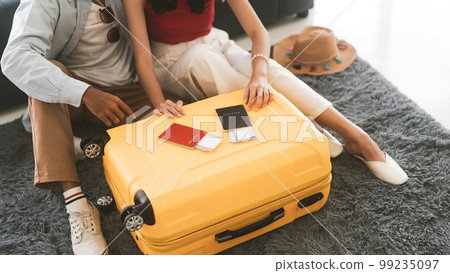 Young adult southeast asian couple hand place on luggage with passport for holidays travel Young adult southeast asian couple hand place on luggage with passport for holidays travel 99235097