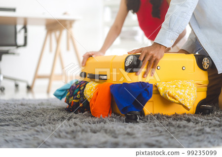 Couple hand place on full of cloth luggage with for getting ready for holidays travel trip Couple hand place on full of cloth luggage with for getting ready for holidays travel trip 99235099