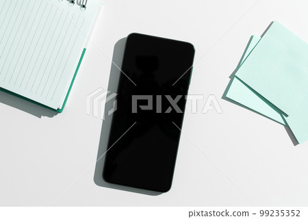 Mobile Phone Screen With Important Ideas On It And Note Sticked On It On Desk With Notebook And Marker. Cellphone With Crutial Informations And Memo Attached To It. Mobile Phone Screen With Important Ideas On It And Note Sticked On It On Desk With Notebook And Marker. Cellphone With Crutial Informations And Memo Attached To It. 99235352