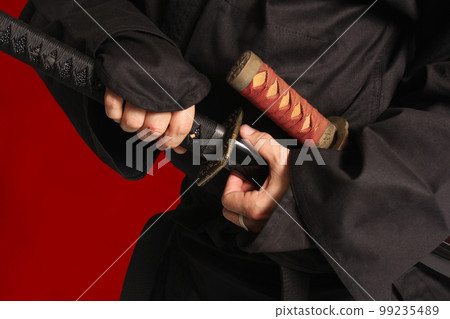 Man Removing Japanese Katana Blade From Scabbard Man Removing Japanese Katana Blade From Scabbard 99235489
