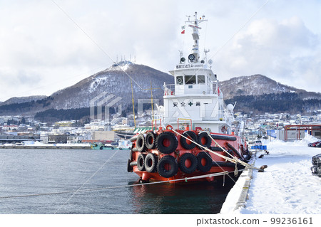 拍攝冬季停泊在北海道函館市函館港的大型拖船和函館山的風景 99236161