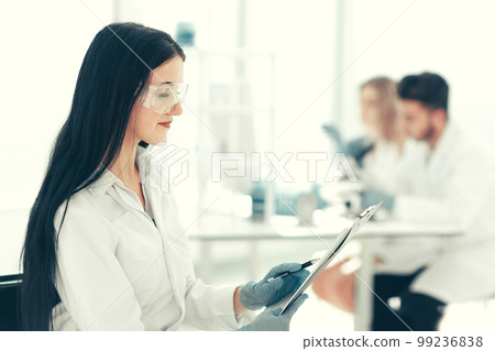 close up. woman scientist reading notes in a laboratory journal close up. woman scientist reading notes in a laboratory journal 99236838