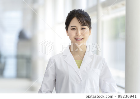 A smiling young woman in a white coat looking at the camera portrait A smiling young woman in a white coat looking at the camera portrait 99236941