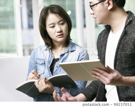 young asian man and woman discussing business in office using digital tablet young asian man and woman discussing business in office using digital tablet 99237051