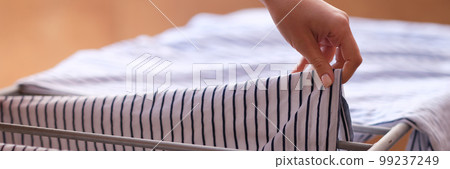 Woman hands hanging clothes to dry on dryer 99237249