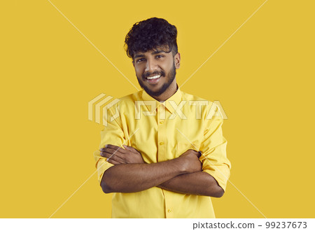 Young ethnic Indian man in stylish shirt smiling broadly posing with arms crossed over chest 99237673