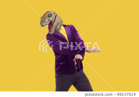 Man wearing dinosaur head mask dancing on yellow background 99237814