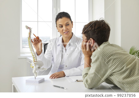 Interested boy child listens attentively to doctor who talks about scoliosis of spine. 99237856