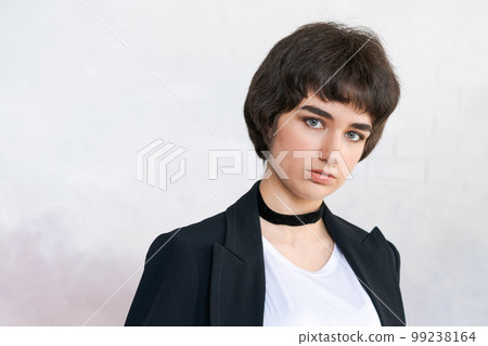 Portrait girl in black jacket with checker around her neck against wall. Pretty Portrait girl in black jacket with checker around her neck against wall. Pretty 99238164