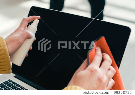 woman wiping the laptop screen with an antiseptic napkin. woman wiping the laptop screen with an antiseptic napkin. 99238733