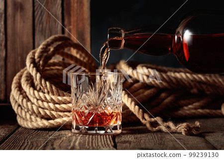 Rum, cognac, or whiskey is poured into a crystal glass. 99239130
