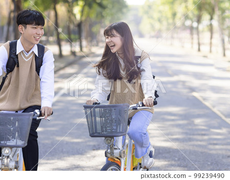 Happy teenager students riding bicycle the school Happy teenager students riding bicycle the school 99239490