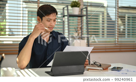 Smart businessman reading reports, working on financial and marketing project at modern home office 99240961