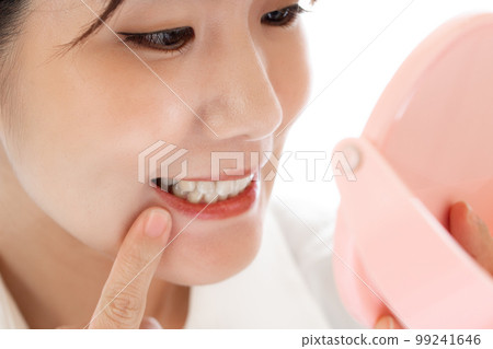 Japanese woman checking her teeth in the mirror Japanese woman checking her teeth in the mirror 99241646