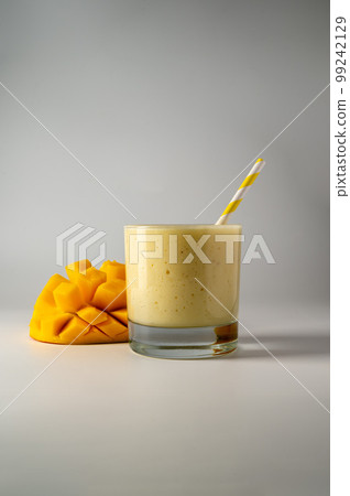 Glass of mango, banana and yoghurt smoothie with a straw. Glass of mango, banana and yoghurt smoothie with a straw. 99242129