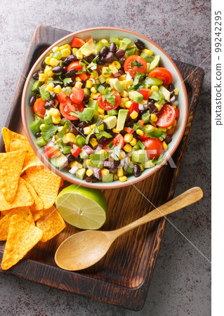 Cowboy texac caviar is a traditional American salad made with black beans, garlic, onion, bell peppers, jalapenos, corn, coriander closeup in the bowl. Vertical top view Cowboy texac caviar is a traditional American salad made with black beans, garlic, onion, bell peppers, jalapenos, corn, coriander closeup in the bowl. Vertical top view 99242295