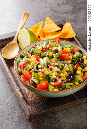 Cowboy texac caviar is a traditional American salad made with black beans, garlic, onion, bell peppers, jalapenos, corn, coriander closeup in the bowl. Vertical Cowboy texac caviar is a traditional American salad made with black beans, garlic, onion, bell peppers, jalapenos, corn, coriander closeup in the bowl. Vertical 99242302