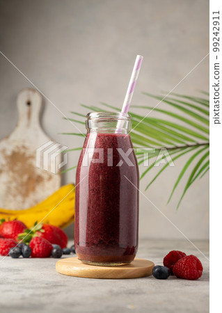 Bottle of berry smoothie in a glass. Strawberry, banana, blueberry healthy drink. Copy space. 99242911