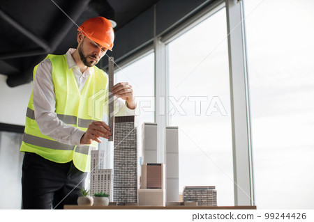 Bearded engineer in protective helmet working on building complex prototype project Bearded engineer in protective helmet working on building complex prototype project 99244426