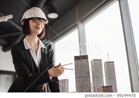 Young female engineer in protective helmet working on building complex prototype project 99244478