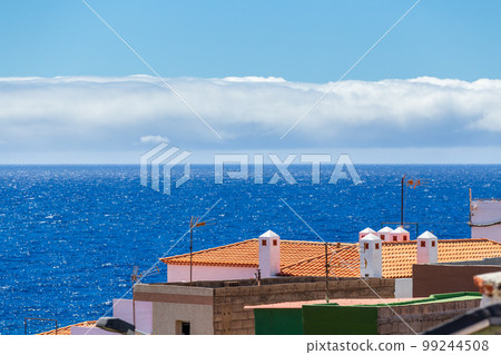 Orange roofs of buildings with blue sea and sky on background Orange roofs of buildings with blue sea and sky on background 99244508