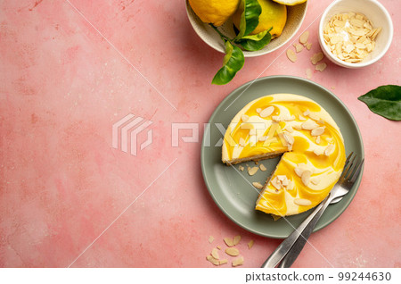 Lemon cheesecake tart or pie, with fresh lemons and cup of coffee, pink background. Copy space 99244630