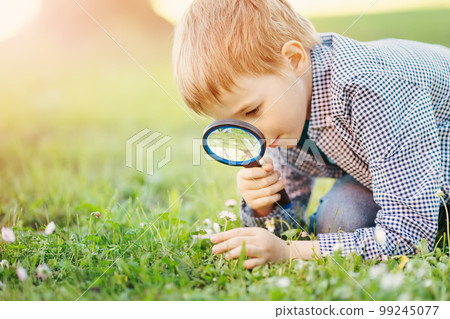 Boy with magnifying glass exploring the nature. 99245077