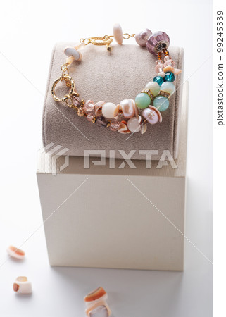 author gold  plated bracelete with pearls and gemstones demonstrated against white background. fashion and jewelry concept 99245339