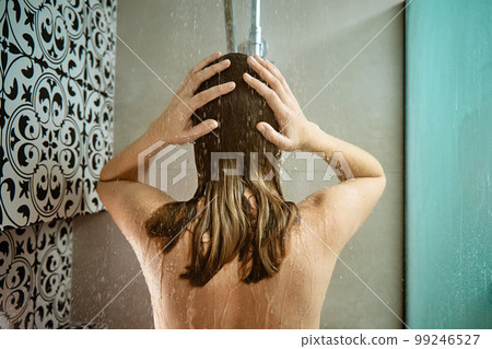 Back view of naked woman taking shower in shower stall. Woman washing her hairs in bathroom. Morning hygiene 99246527