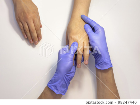 Manicure master applies organic eco peeling on woman hand's skin, doing massage. Nail master wears purple gloves.Nail hand spa treatment, care. Beauty procedure in process. Closeup Horizontal plane. 99247440