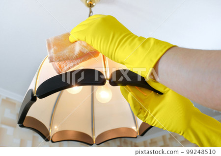 The cleaner wipes the dust from the chandelier. House cleaning 99248510