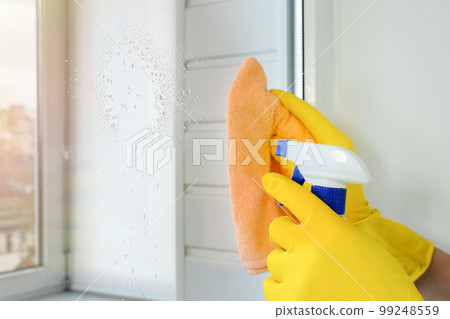 Female hands in yellow rubber gloves wash the windows. Cleaning concept 99248559