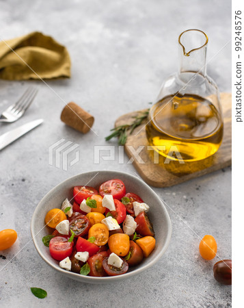 Fresh vegetable salad with feta cheese in a bowl. Healthy food diet. gray concrete background, vertical image, side view Fresh vegetable salad with feta cheese in a bowl. Healthy food diet. gray concrete background, vertical image, side view 99248576