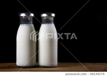 Two glass bottles of fresh milk on a black background 99248579