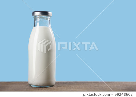Bottle of milk on a wooden table on a blue background 99248602